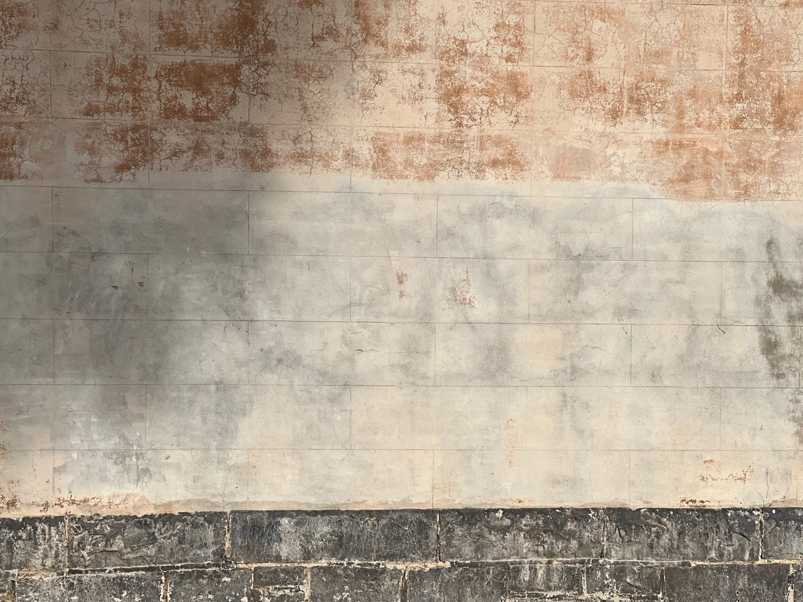 Rustic weathered stucco wall showing a textured and aged surface, ideal for background use.
