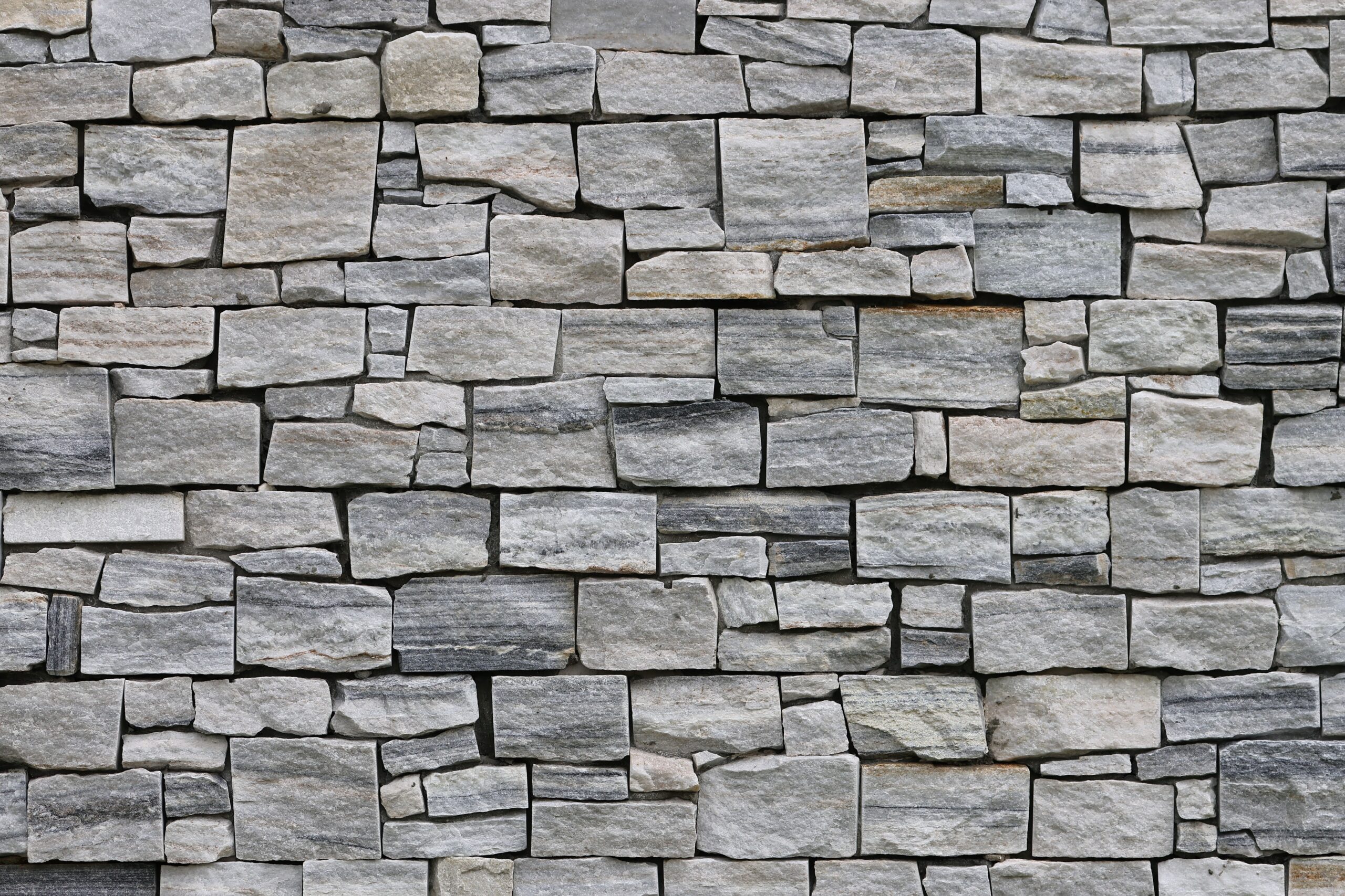 Detailed texture of a rustic stone wall, perfect for backgrounds or wallpaper.