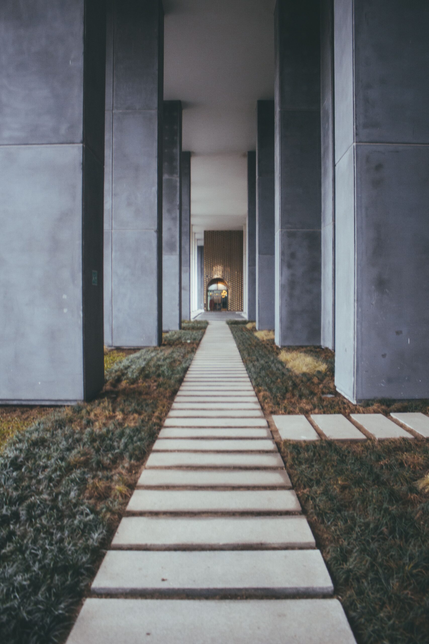 Symmetrical concrete columns framing a pathway in an outdoor urban setting.
