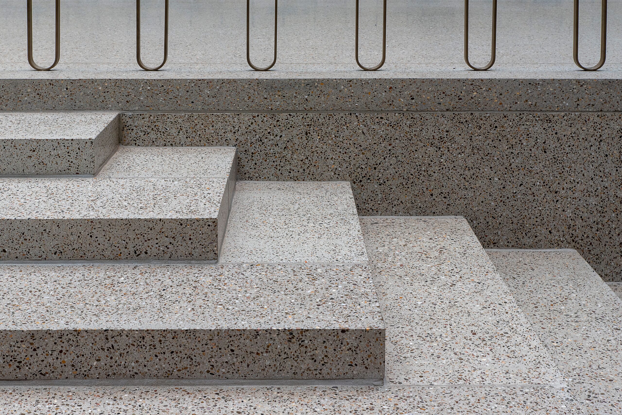 Minimalist concrete staircase featuring terrazzo texture and sleek metal railings.
