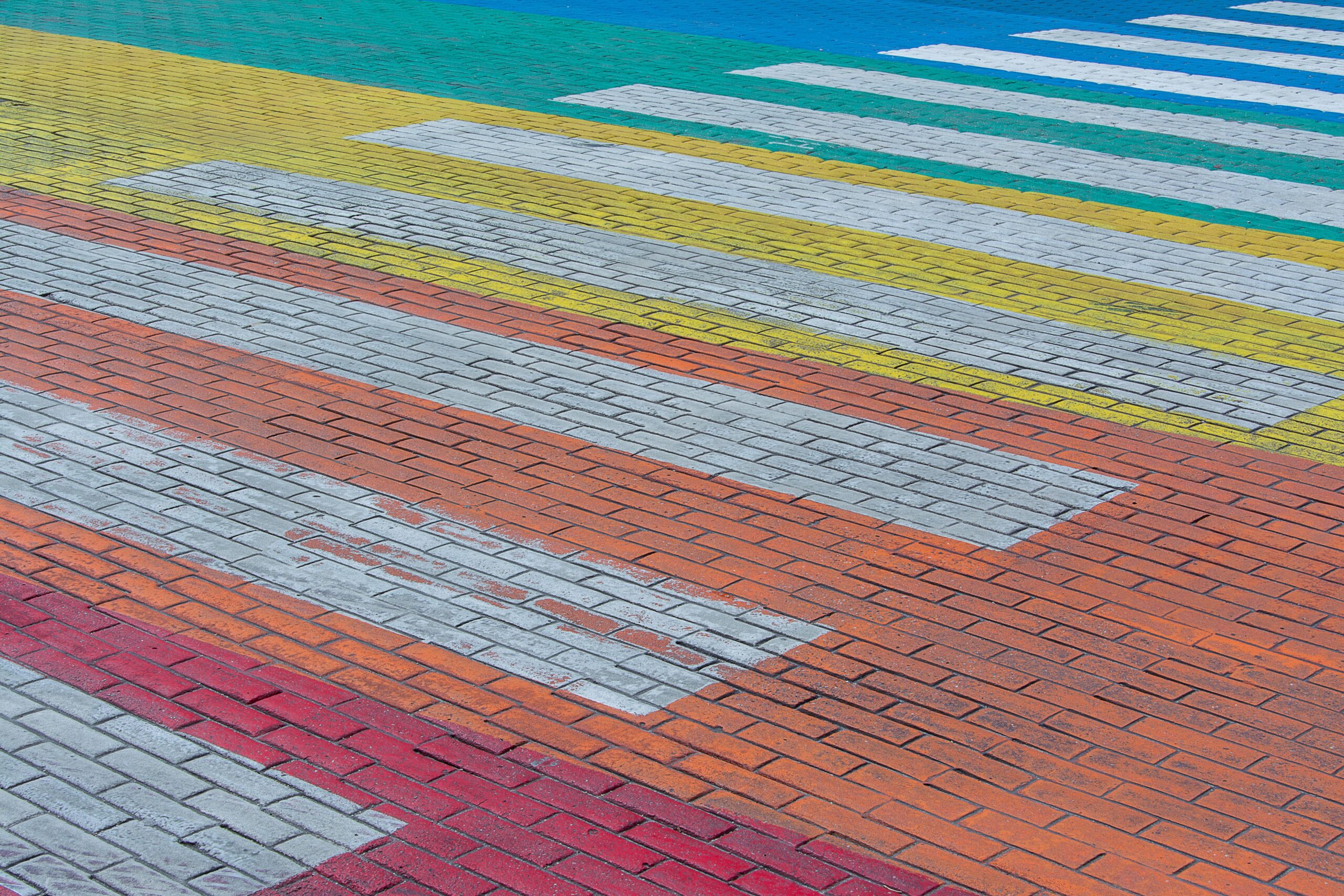 A vibrant close-up of a colorful paver crosswalk in an urban setting.
